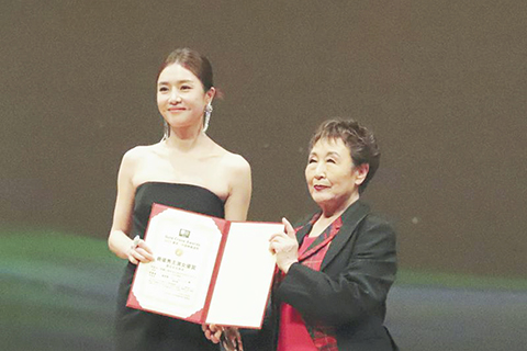 ◎ 十月二十八日,在日本東京,演員曾夢雪(左)上台領獎。曾夢雪憑藉《分手清單》榮獲「金鶴獎」最佳女主角獎。(新華社記者 李子越 攝)