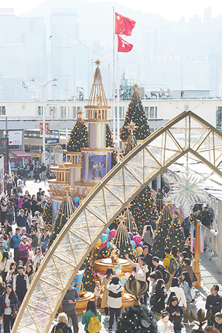 ◎ 十二月廿七日,聖誕節後的周末,香港多區仍洋溢節日氣氛,不少市民與旅客趁假日到訪商場及街頭聖誕裝飾前拍照留念。圖為遊客與市民在海港城聖誕裝飾前拍照打卡。(香港中通社記者陳奕啟 攝)