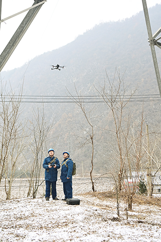 ◎ 一月二十九日,國網寶雞供電公司輸電運檢中心秦嶺輸電運維班班長周紅亮(左)、副班長令雲在寶雞市鳳縣黃牛鋪鎮東河橋村附近使用無人機檢查線路覆冰情況。(新華社記者鄒競一 攝)