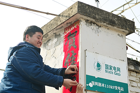 ◎ 一月二十八日,國網寶雞供電公司輸電運檢中心秦嶺輸電運維班成員趙鶴在變電站張貼新春對聯。(新華社記者鄒競一 攝)