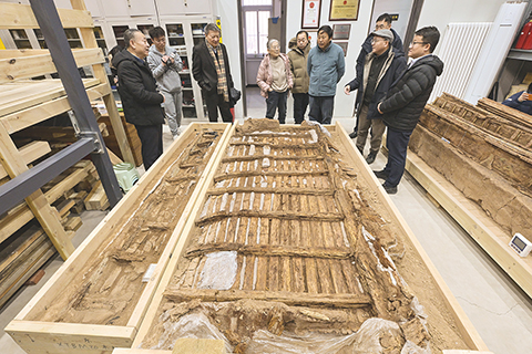 ◎ 專家們在實驗室考古方艙內察看墓葬M20出土的完整木榻(二月一日攝)。(新華社記者李賀 攝)