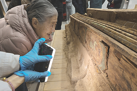 ◎ 中國社會科學院考古研究所研究員安家瑤在實驗室考古方艙內仔細察看墓葬M20出土木棺座上的彩繪圖案(二月一日攝)。(新華社記者李賀 攝)